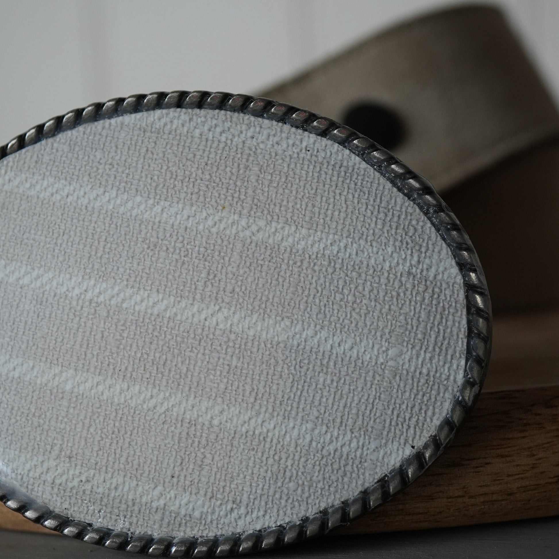 Round fabric pad with a wooden base on a neutral background