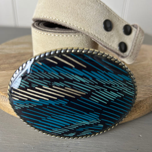 Belt with a blue and black patterned buckle on a wooden surface