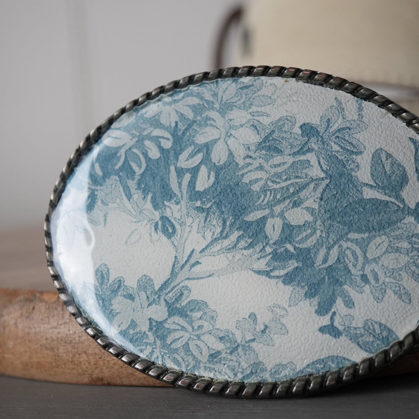 Decorative oval object with floral pattern on a wooden surface